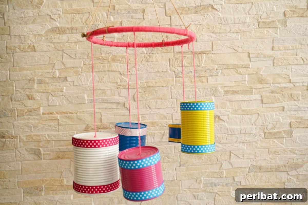 Transform Tin Cans into Melodious Wind Chimes 17 A finished tin can wind chime, featuring multiple colorful cans hanging from a vibrant pink hoop, gracefully suspended against a textured brick wall, ready for display