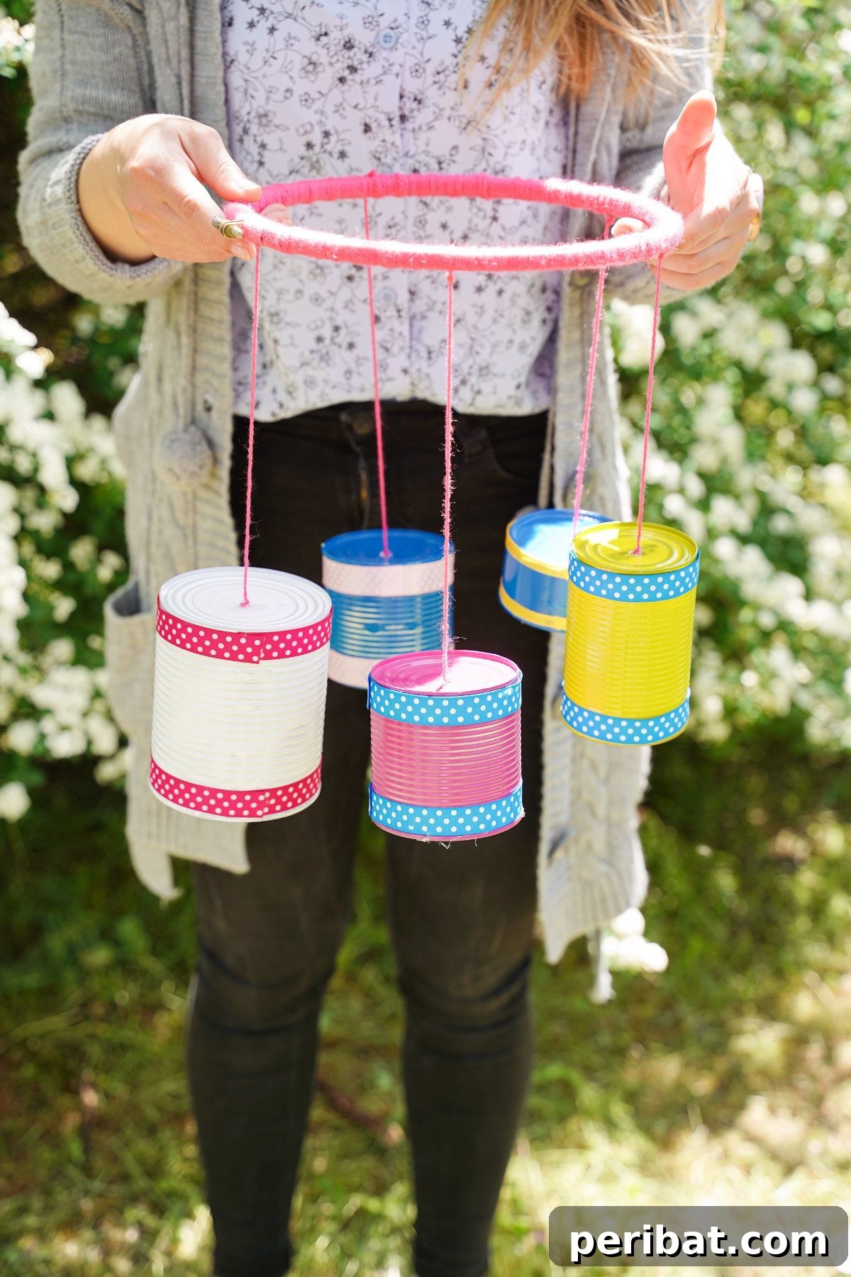 Transform Tin Cans into Melodious Wind Chimes 3 A woman proudly showcasing her newly crafted colorful tin can wind chime, emphasizing the handmade aspect