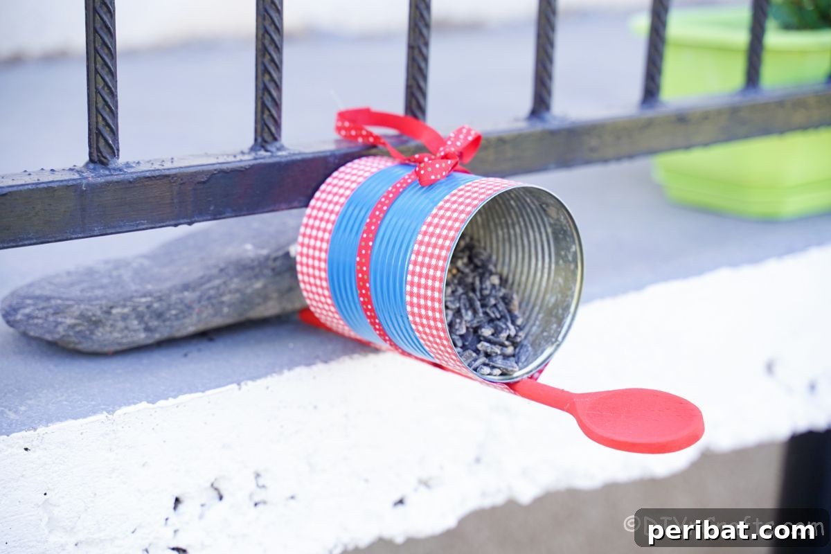 Sweet DIY Tin Can Bird Feeder 14 The finished tin can bird feeder, painted and adorned, is charmingly propped against a porch railing, awaiting its first feathered visitors.