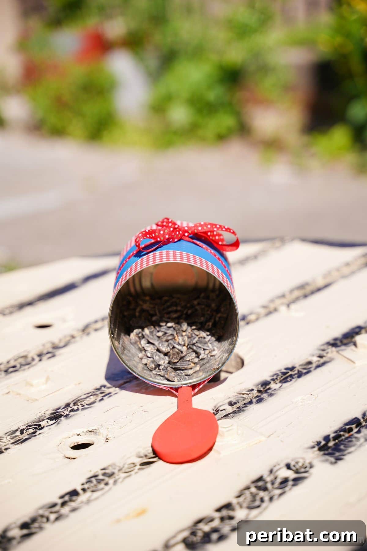 Sweet DIY Tin Can Bird Feeder 3 Close-up of a red painted wooden spoon serving as a sturdy perch on a tin can bird feeder, placed on a rustic table.