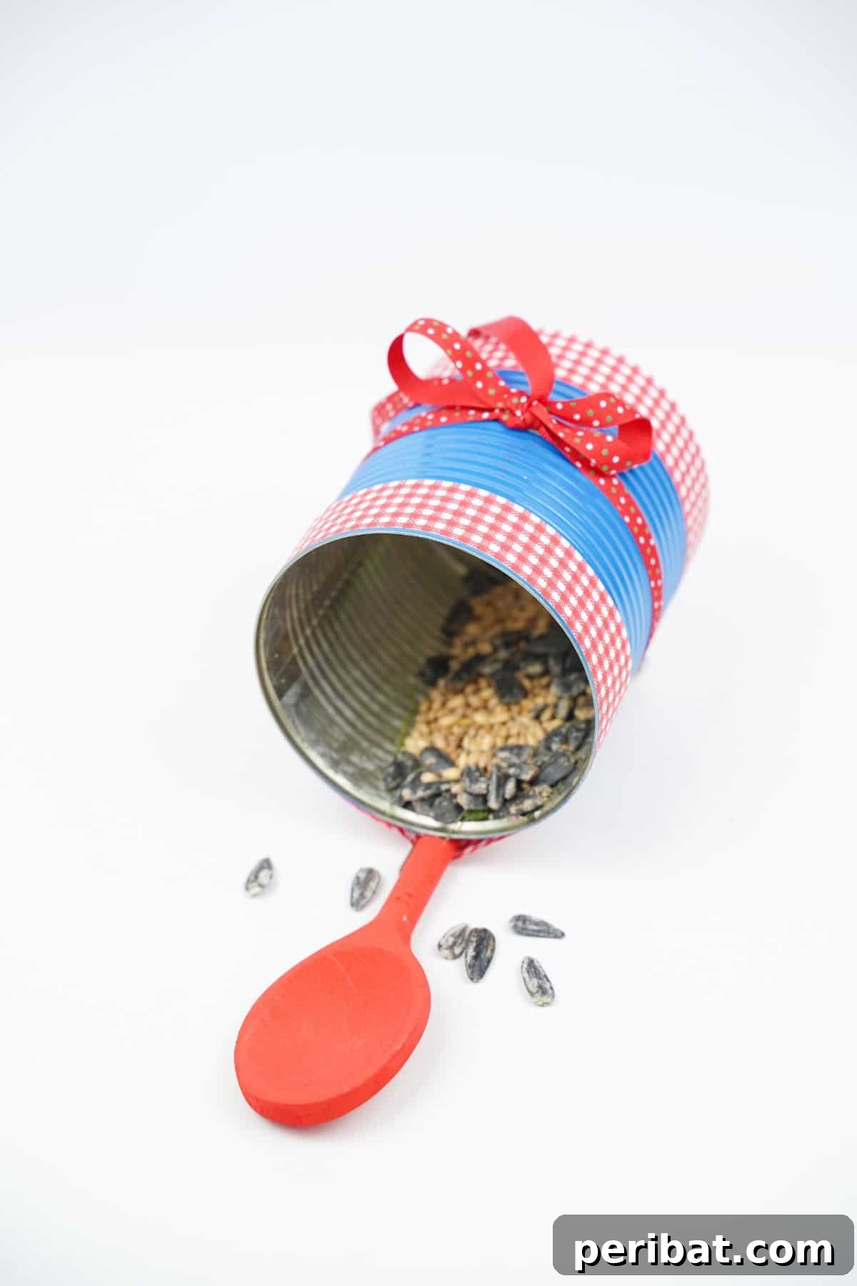 Sweet DIY Tin Can Bird Feeder 15 A vibrant red and blue tin can bird feeder rests on a pristine white table, showcasing its colorful design and ready for use.