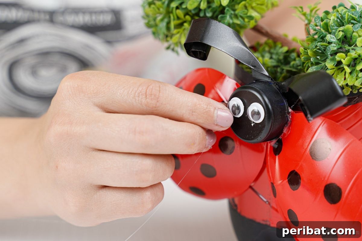 Upcycled Ladybug Garden Gems 20 googly eyes being put onto lid of ladybug planter