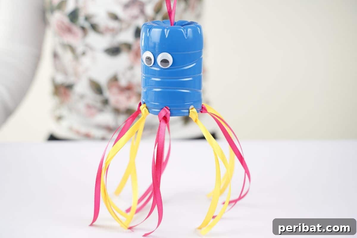Vibrant Upcycled Bottle Wind Streamer 14 Blue windsock with ribbons held above a white table, showing the hanging loop