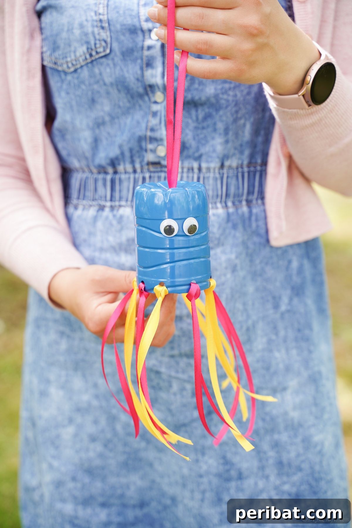 Vibrant Upcycled Bottle Wind Streamer 3 Woman holding a blue and pink plastic bottle windsock