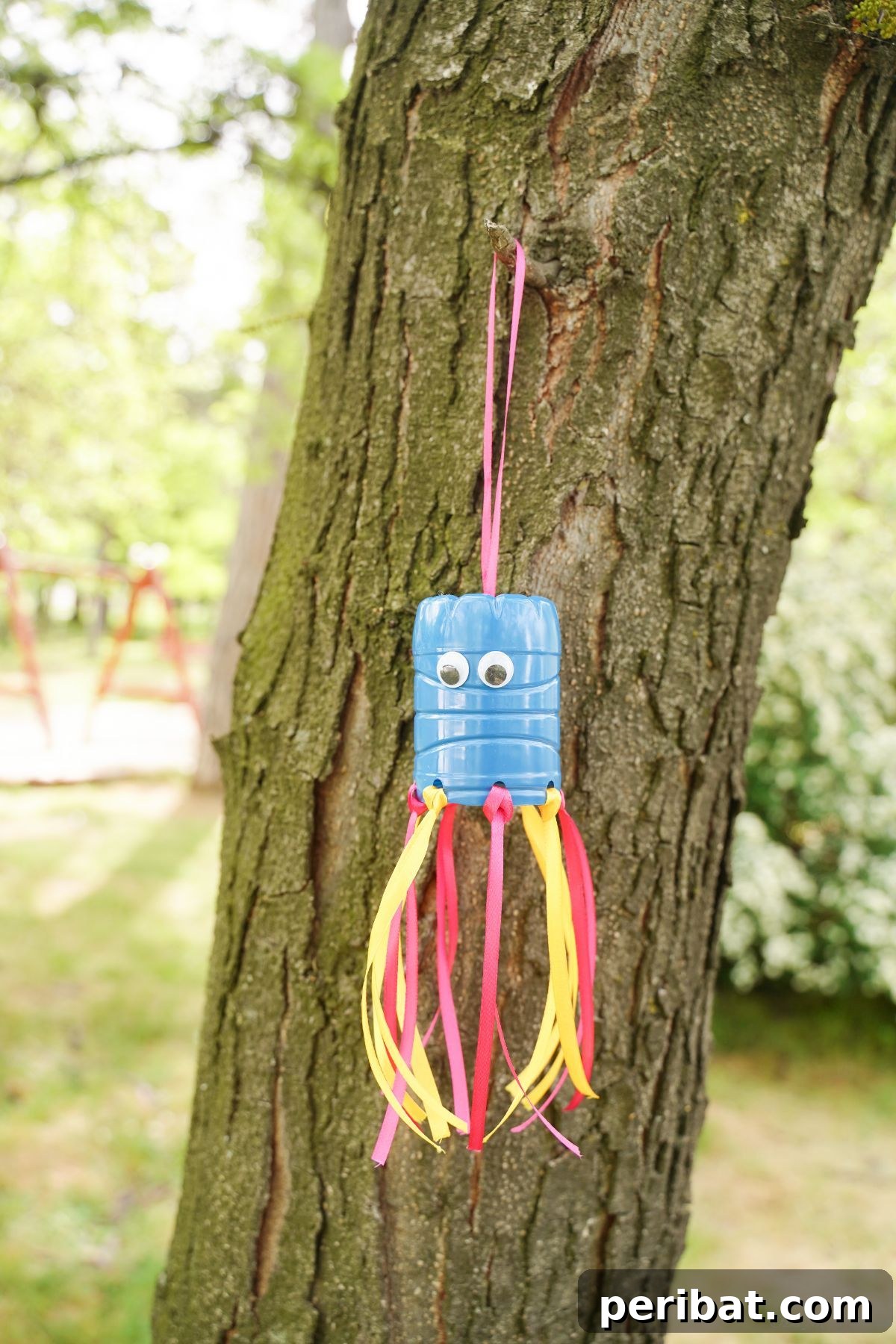 Vibrant Upcycled Bottle Wind Streamer 18 Blue, pink, and yellow plastic bottle windsock hanging in a tree