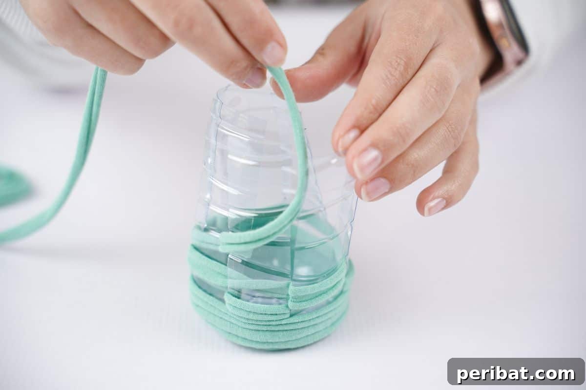 Upcycled Plastic Bottle Desk Organizer 11 Vivid green yarn being meticulously wrapped and woven around a prepared plastic bottle, creating the initial colorful section.