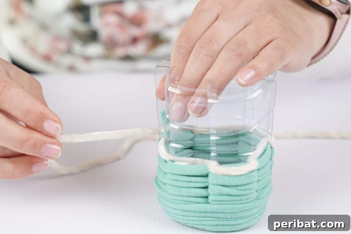 Upcycled Plastic Bottle Desk Organizer 12 Close-up of white and green yarn being neatly tied together on the plastic cup, signifying a color transition in the weaving.