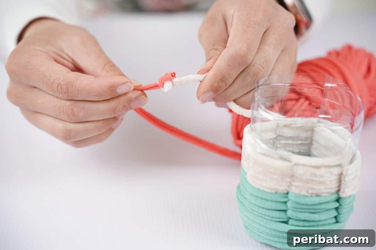 Upcycled Plastic Bottle Desk Organizer 13 Detail shot of white and pink yarn being tied together, marking the transition to the final color for the pencil holder.