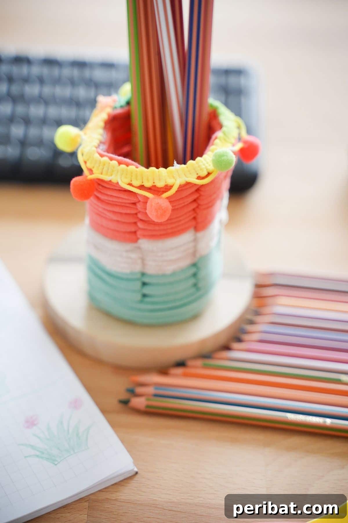Upcycled Plastic Bottle Desk Organizer 16 The vibrant striped DIY pencil holder resting on a desk, surrounded by a collection of colored pencils, ready for artistic endeavors.