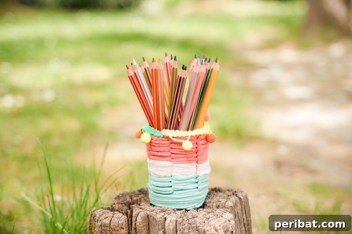 Upcycled Plastic Bottle Desk Organizer 17 A colorful striped yarn pencil cup, handcrafted from a plastic bottle, sitting charmingly on a wooden tree stump, highlighting its rustic appeal.