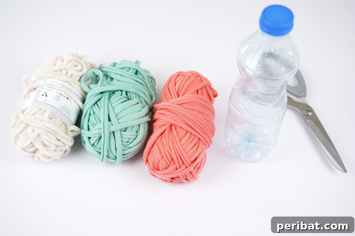 Upcycled Plastic Bottle Desk Organizer 7 Crafting supplies laid out on a white table: pink, green, and white yarn, a plastic bottle, and scissors, ready for the DIY project.