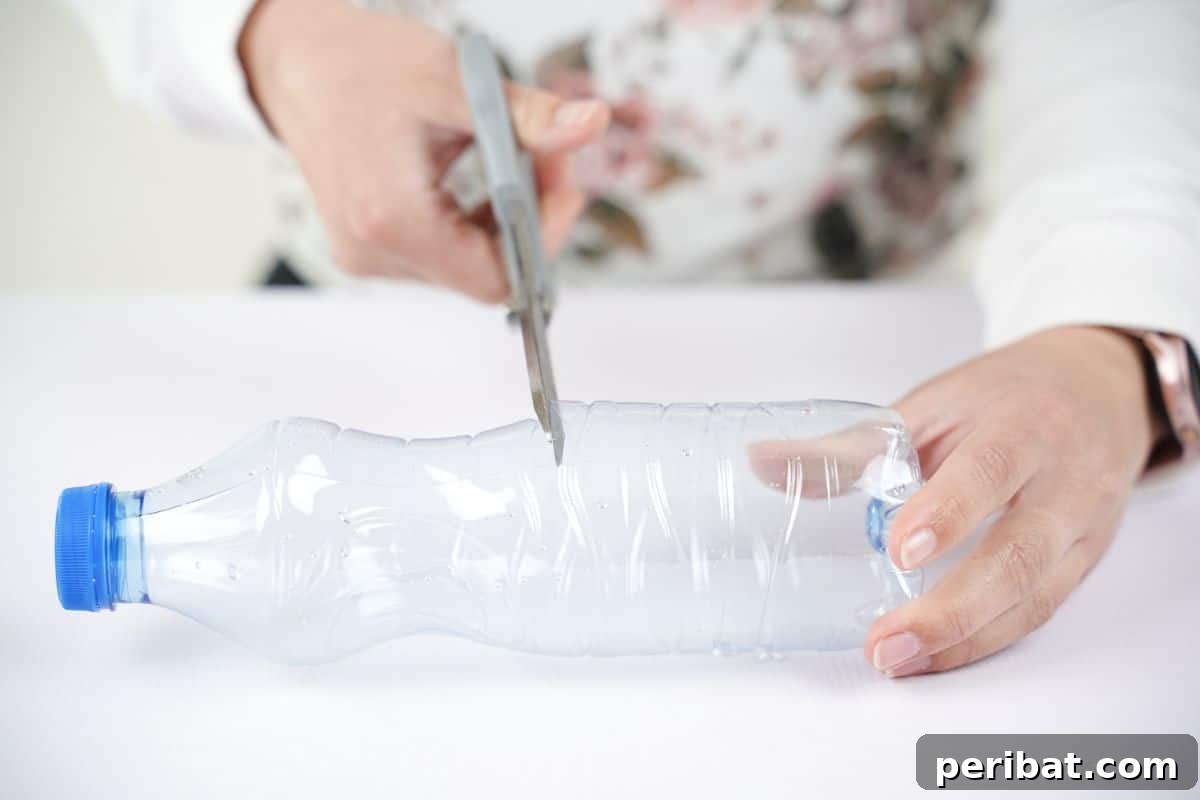 Upcycled Plastic Bottle Desk Organizer 8 A hand expertly holding gray scissors, precisely cutting a plastic bottle in half, preparing it for the upcycling project.