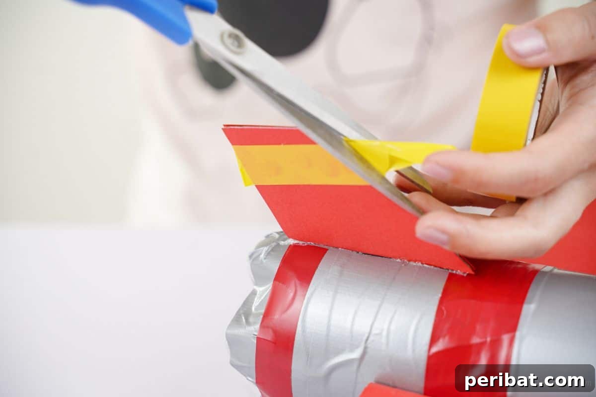 Blue scissors trimming yellow washi tape on the end of an airplane wing, adding decorative stripes.