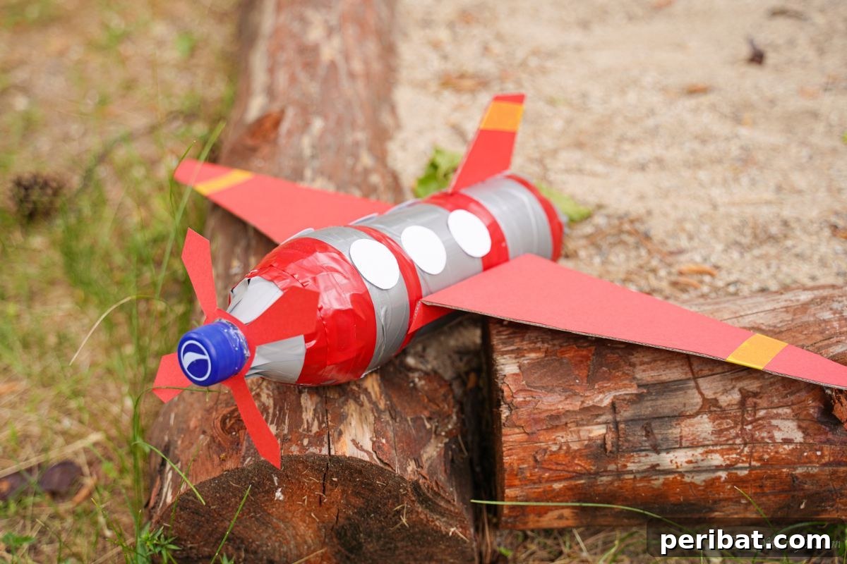 Upcycle Bottles Into Fun Toy Airplanes 3 A colorful toy airplane, crafted from a plastic bottle, rests playfully on the edge of playground wood chips.