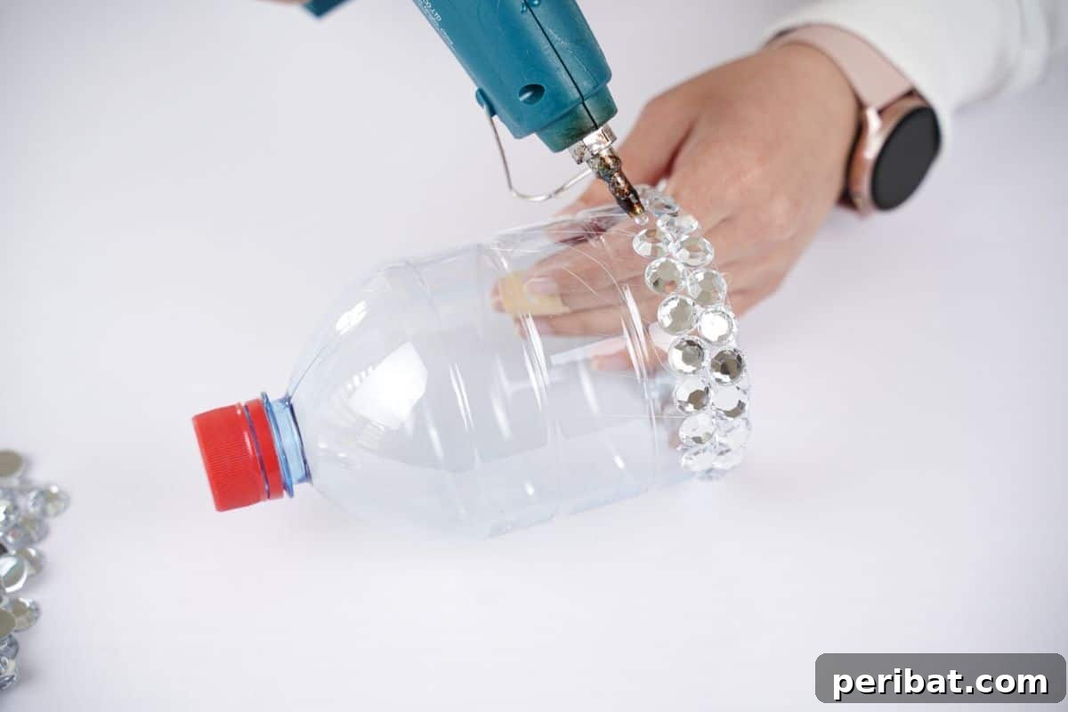Radiant Recycled Rhinestone Vase 10 hand holding glue gun to attach more rhinestones onto plastic bottle