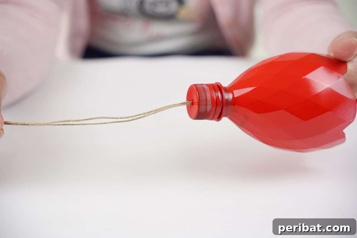Upcycled Bottle Birdhouse 12 Twine strung through a red bottle lid, with the knot secured on the inside for hanging