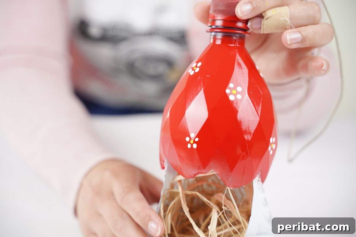 Upcycled Bottle Birdhouse 27 holding red top above white base with raffia