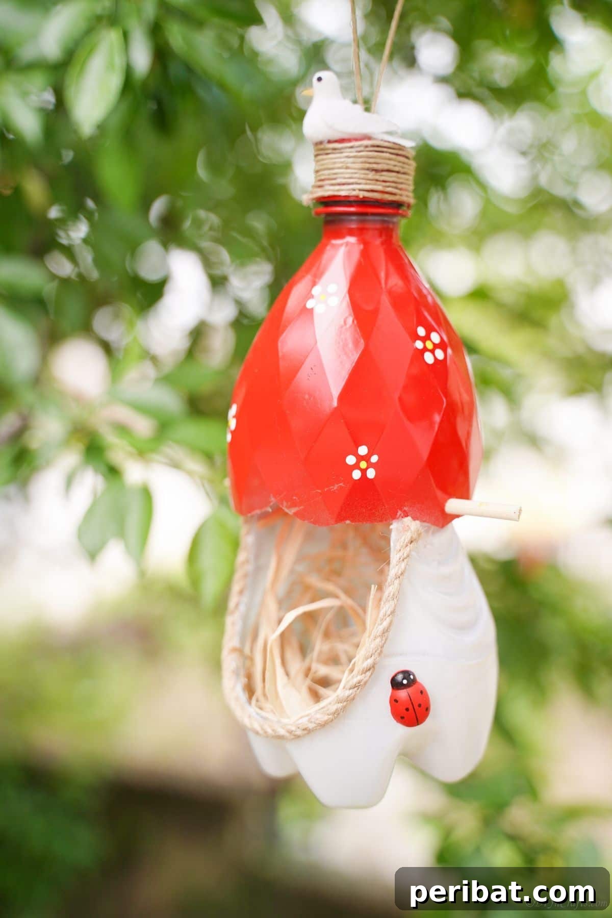Upcycled Bottle Birdhouse 32 A charming bird nest, skillfully crafted from plastic bottles, hanging peacefully in a lush green tree