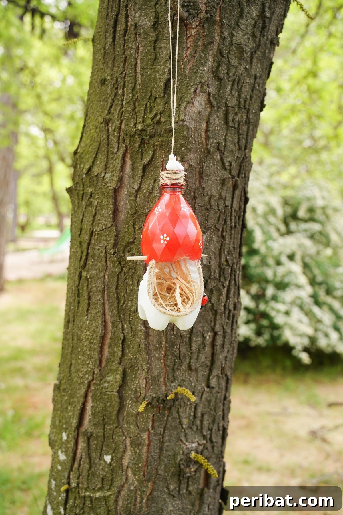 Upcycled Bottle Birdhouse 33 A vibrant red and white plastic bottle bird nest securely installed on a tree, ready to welcome birds