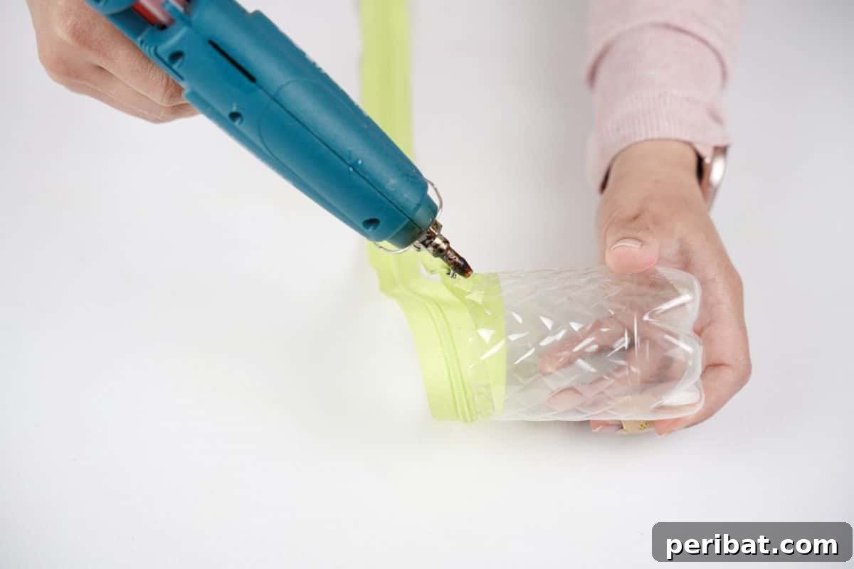 Stitch-Free Upcycled Bottle Stationery Pouch 15 Hot glue gun securing a zipper to a plastic bottle, detailed step-by-step for the DIY pencil case.