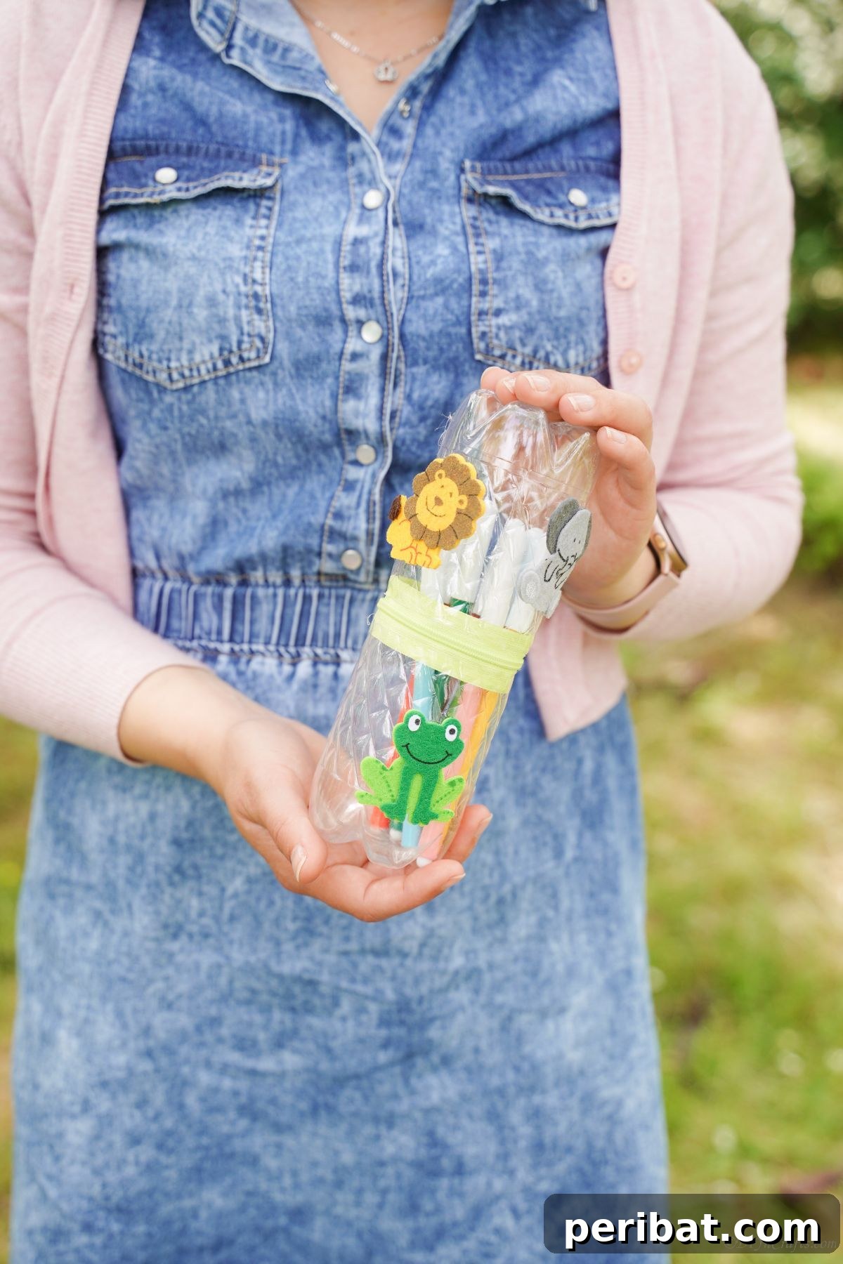 Stitch-Free Upcycled Bottle Stationery Pouch 4 Woman in a blue jumper proudly holding her newly crafted plastic bottle pencil case, demonstrating its functionality.