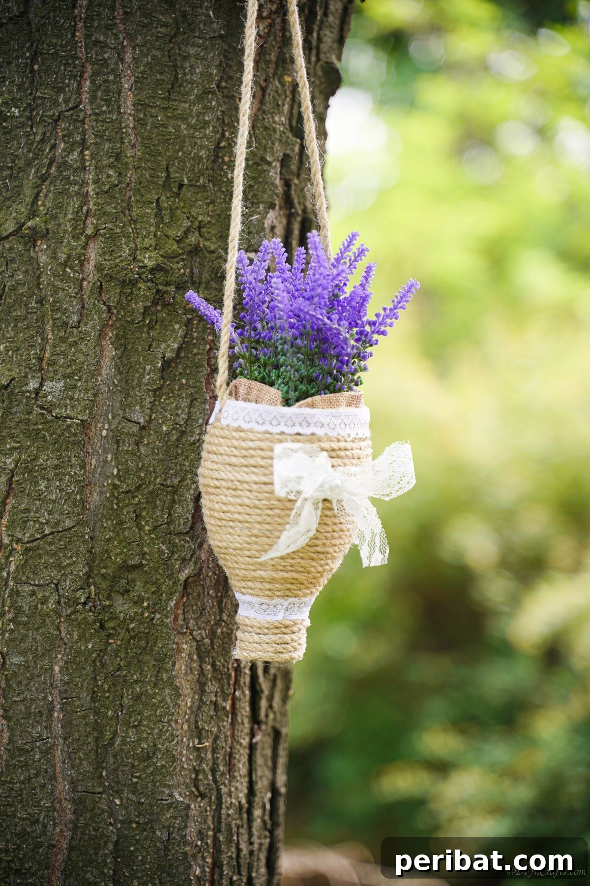 DIY Rustik İp Sarılı Şişe Bahçe Planterları 3 Purple flowers beautifully displayed in a twine hanging planter suspended from a lush green tree branch, highlighting outdoor decor potential.