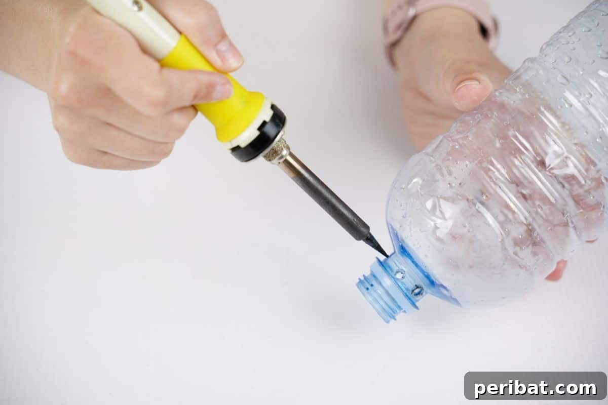 Recycled Bottle Bird Retreat 13 a hand using a soldering iron to create small, precise holes around the neck of a plastic water bottle