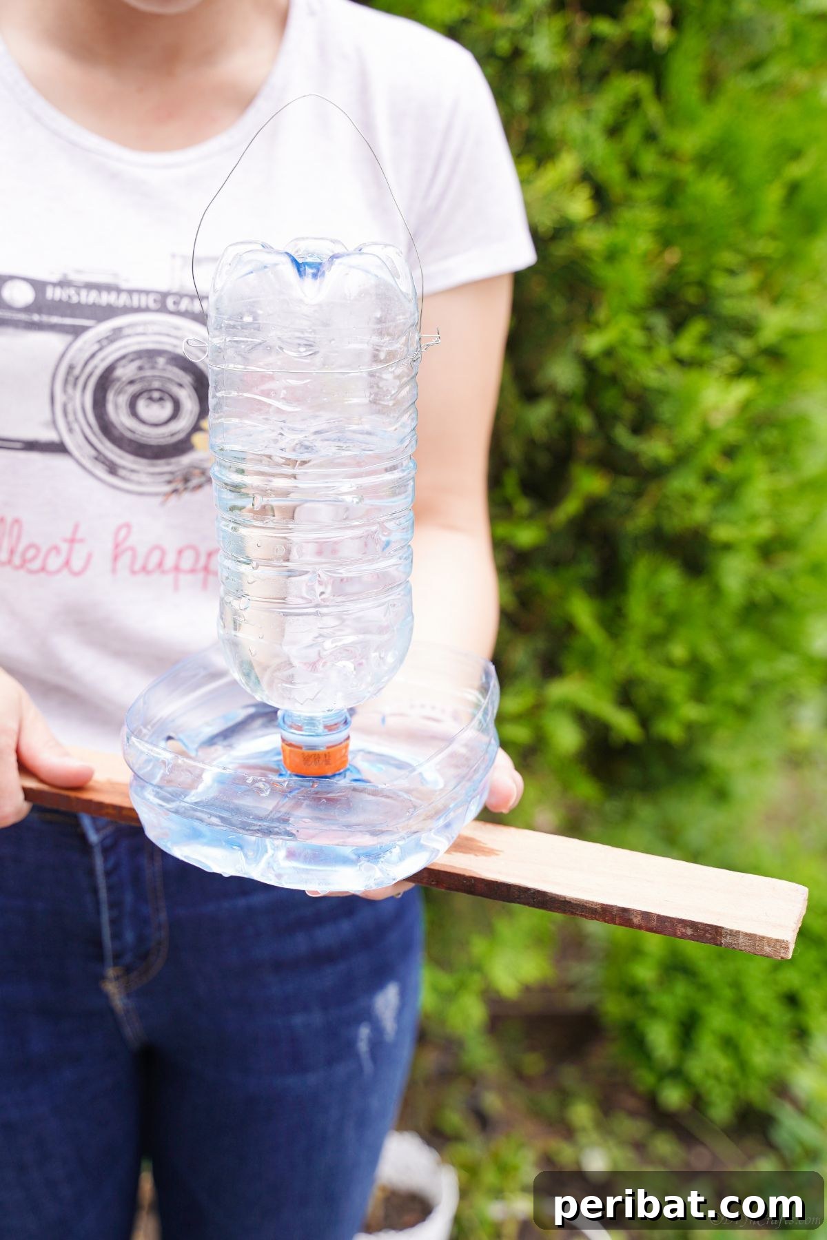Recycled Bottle Bird Retreat 3 woman holding a handmade bird water feeder made from an upcycled plastic bottle, showcasing the simple design