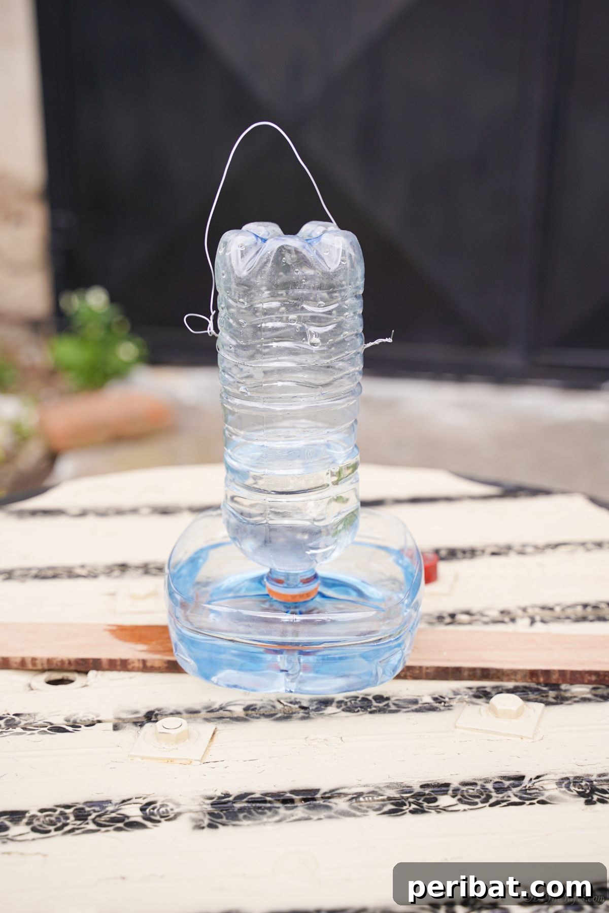 Recycled Bottle Bird Retreat 6 a fully assembled plastic bottle bird feeder filled with water, sitting on a wooden table, ready for placement