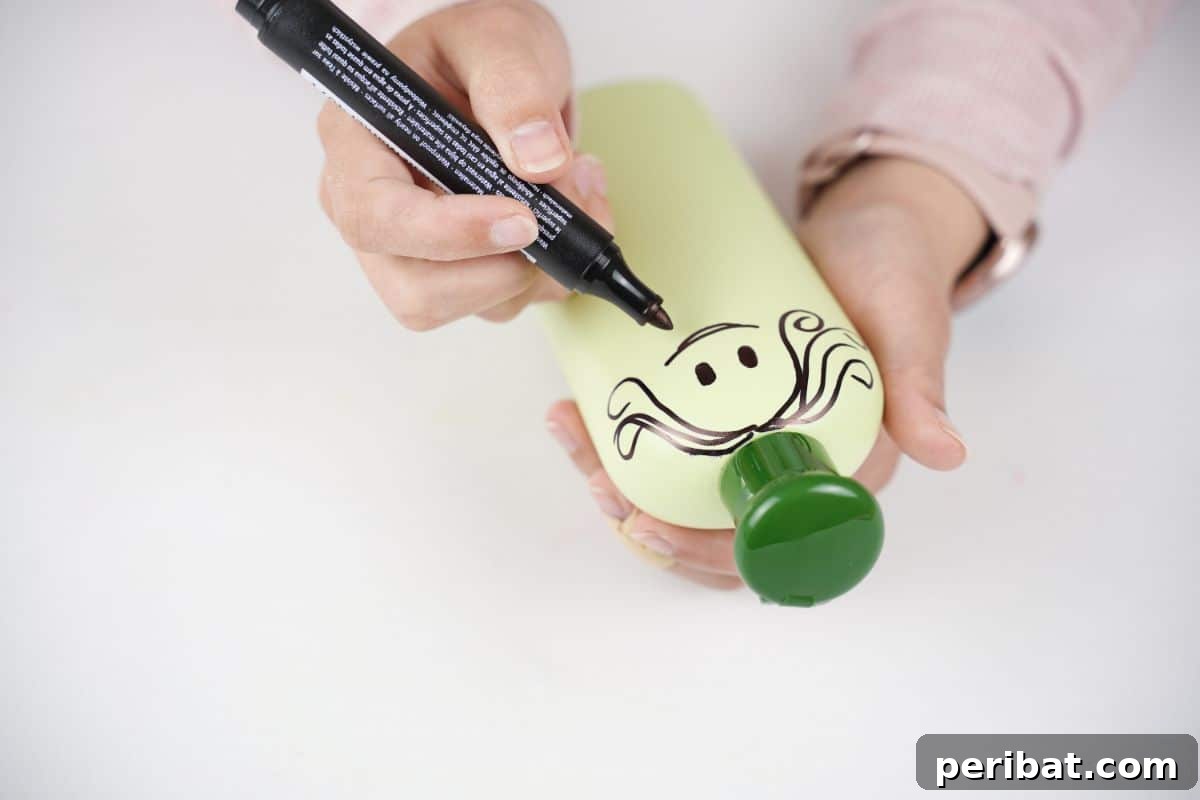 Craft Upcycled Bottle Characters for a DIY Bowling Game 12 A black marker being used to draw a friendly face, including eyes and a mouth, onto a green painted plastic bottle.