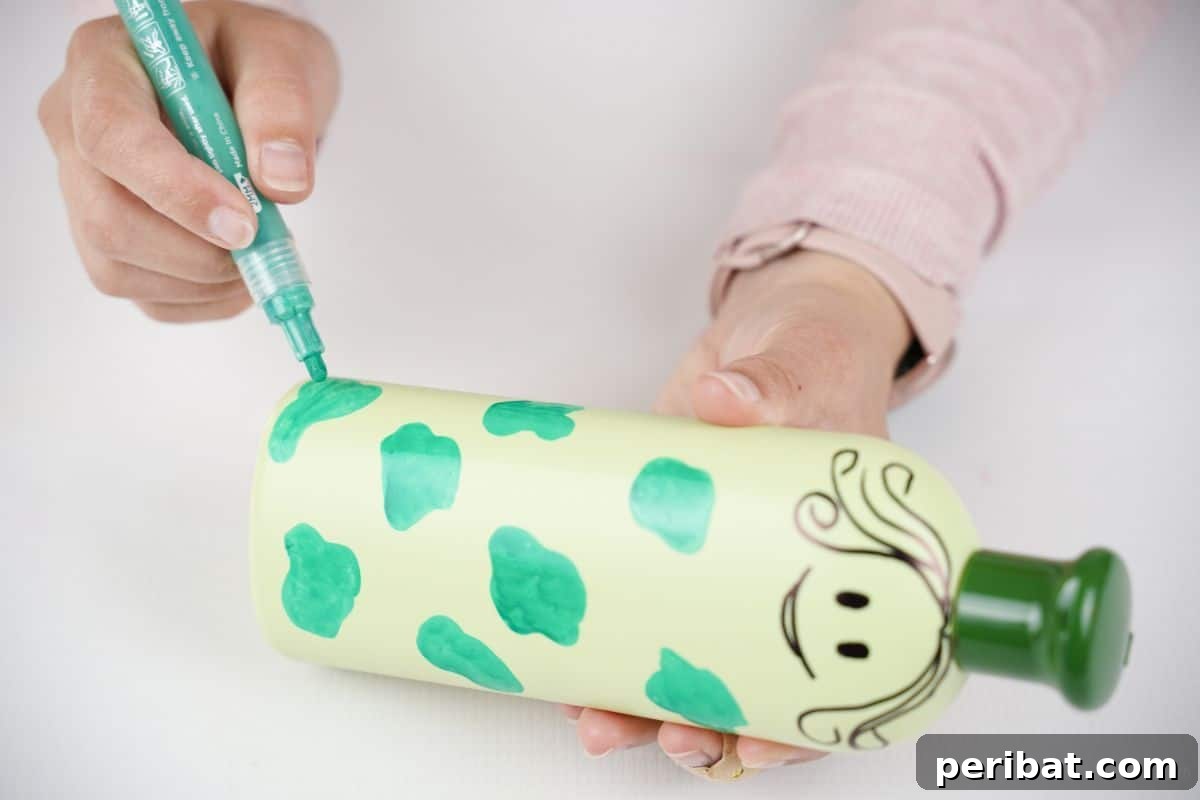 Craft Upcycled Bottle Characters for a DIY Bowling Game 14 Green dots being painted onto a light green plastic bottle, adding a detailed pattern to the character.