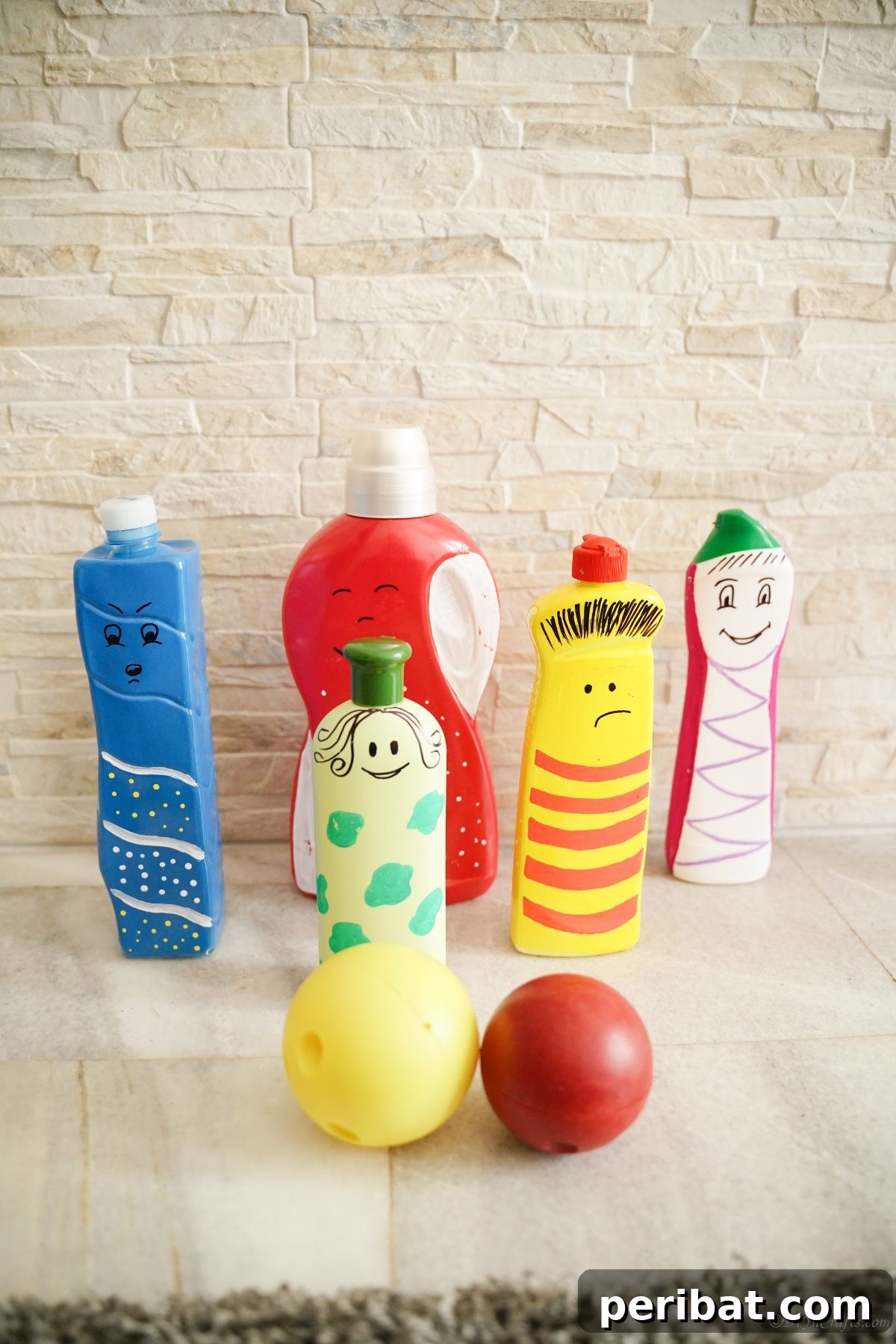 Craft Upcycled Bottle Characters for a DIY Bowling Game 4 Several brightly painted character puppets made from plastic bottles, posed against a light brick wall with small, colorful decorative balls.