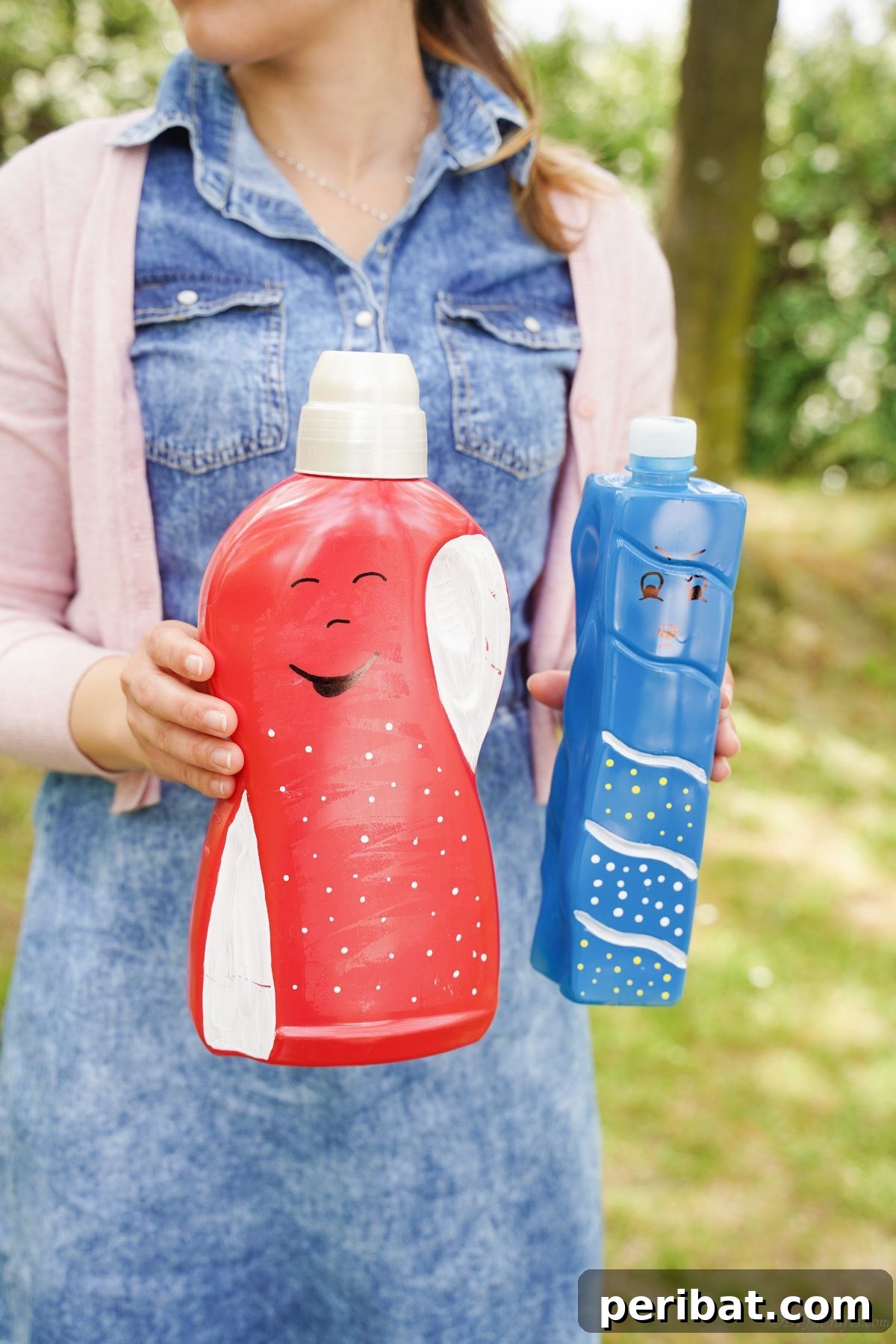 Craft Upcycled Bottle Characters for a DIY Bowling Game 19 A woman in a blue shirt holds several brightly painted plastic bottle puppets, showcasing the variety of characters created.