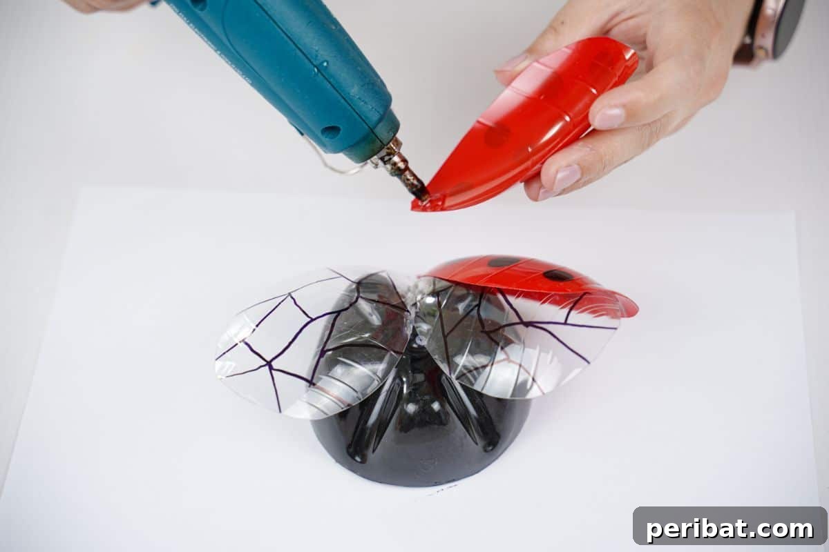 Charming Ladybug Garden Decor from Upcycled Bottles 17 Hot glue is visible on the red and black spotted wings of a ladybug decoration, ready for final attachment.