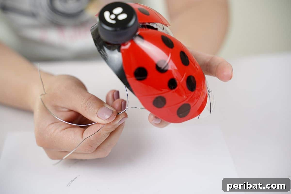 Charming Ladybug Garden Decor from Upcycled Bottles 18 A hand twisting jewelry wire beneath a ladybug decoration, creating a secure attachment for hanging or staking.