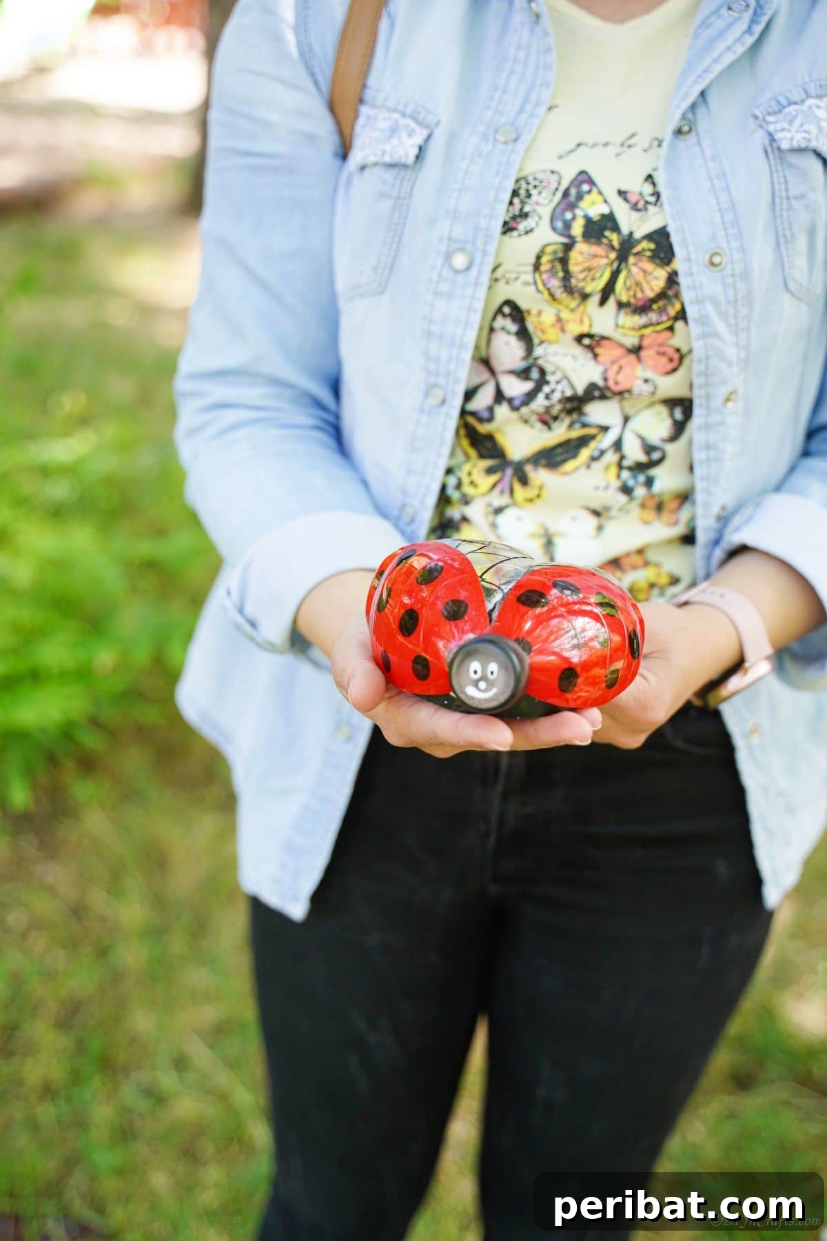 Charming Ladybug Garden Decor from Upcycled Bottles 29 A woman in a blue jacket holding a vibrant plastic bottle ladybug, illustrating the size and visual appeal of the finished craft.