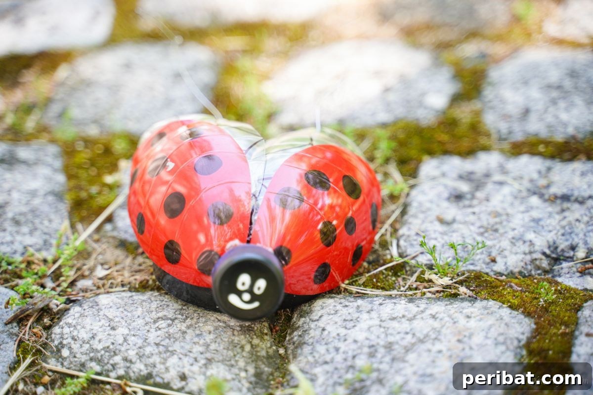 Charming Ladybug Garden Decor from Upcycled Bottles 6 A charming plastic bottle ladybug decoration resting on a cobblestone path in a garden, blending natural textures with vibrant craftwork.