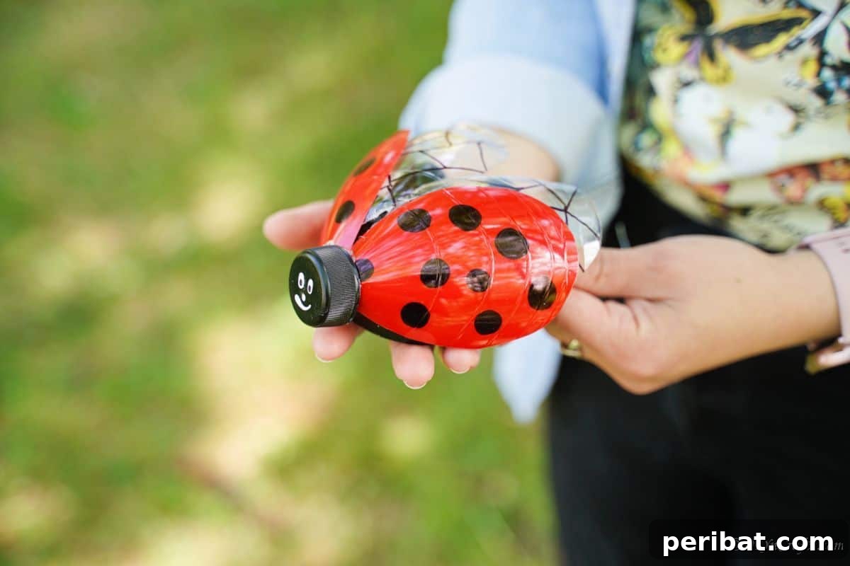 Charming Ladybug Garden Decor from Upcycled Bottles 8 A pair of hands showcasing a freshly painted black and red plastic bottle ladybug decoration, highlighting its vibrant colors.
