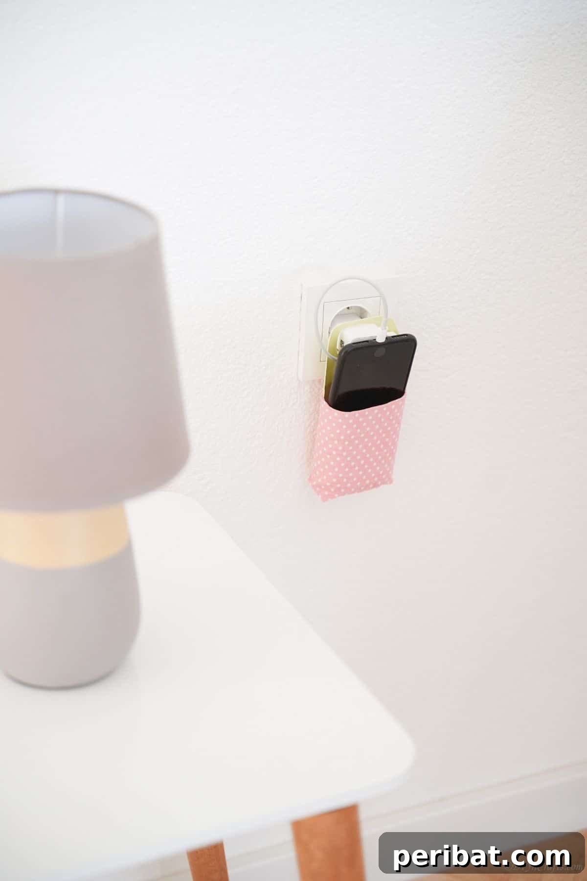 white table with gray lamp next to pink cellphone holder on wall