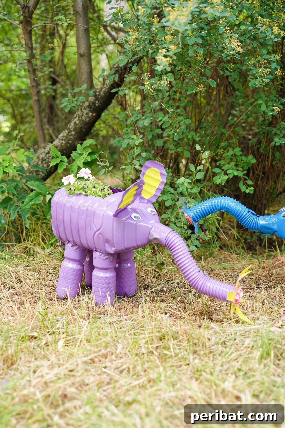 Upcycled Bottles Blossom into Adorable Elephant Planters 4 pink flowers in back of elephant planter