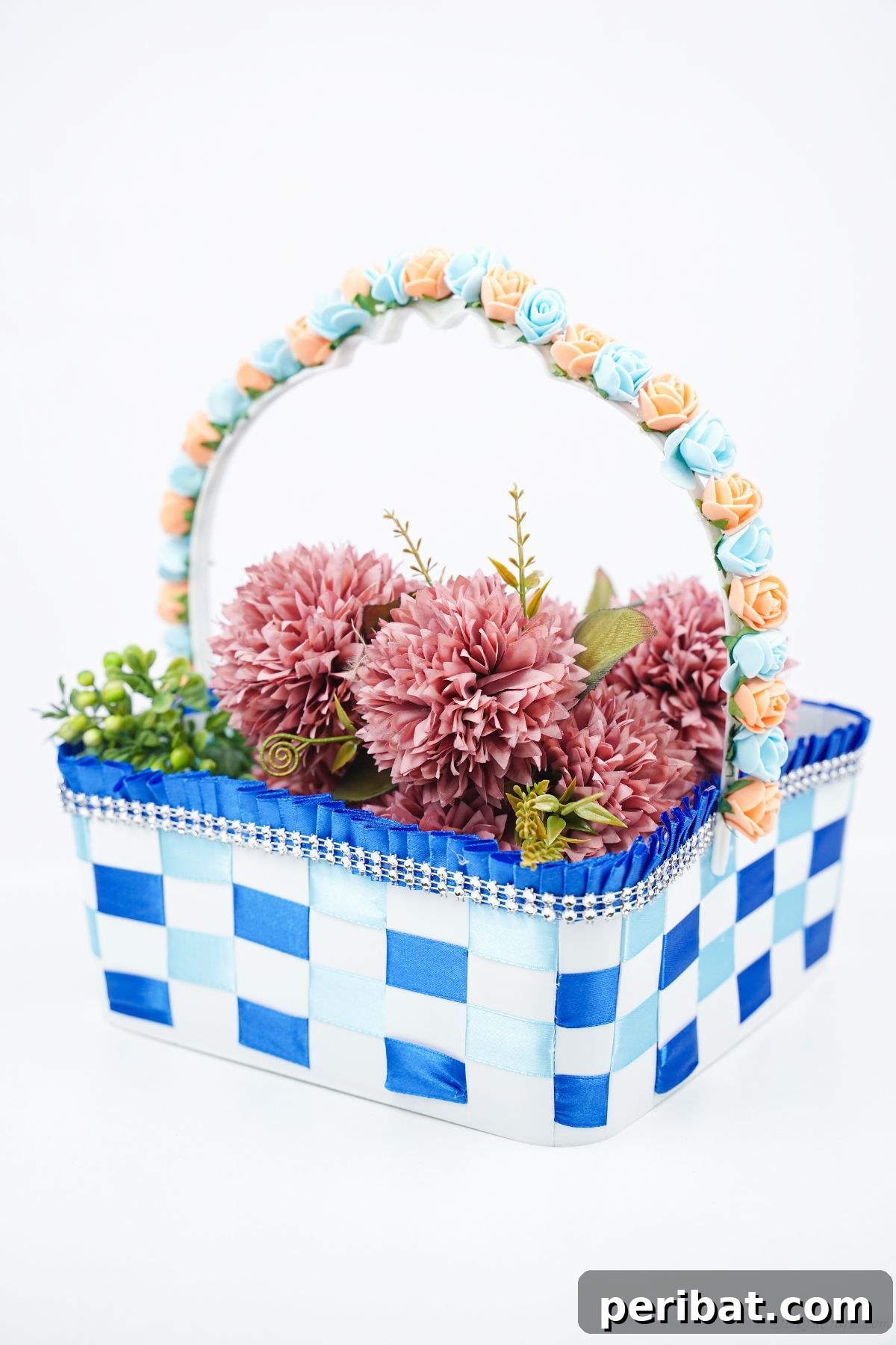 Sweet Treat Pail Transformed Basket 17 Blue and white ribbon basket filled with pink flowers on a white counter, displaying the final decorative product.