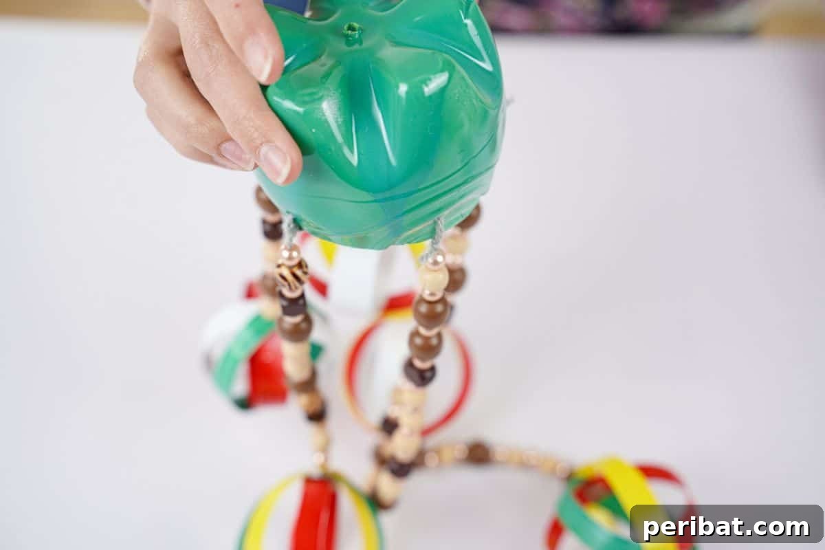 Beaded Bottle Breeze Song 16 hand holding green bottle with beads hanging on white table