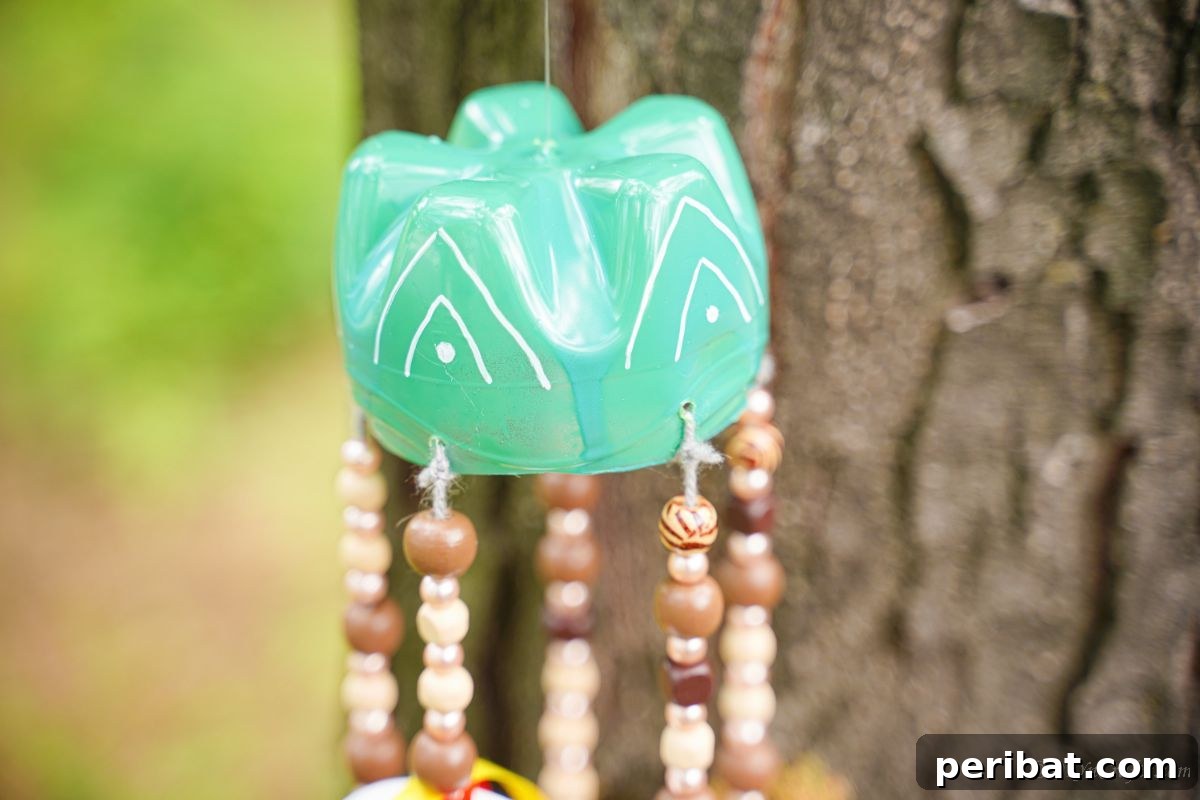 Beaded Bottle Breeze Song 7 green and white top on wind chime in front of tree