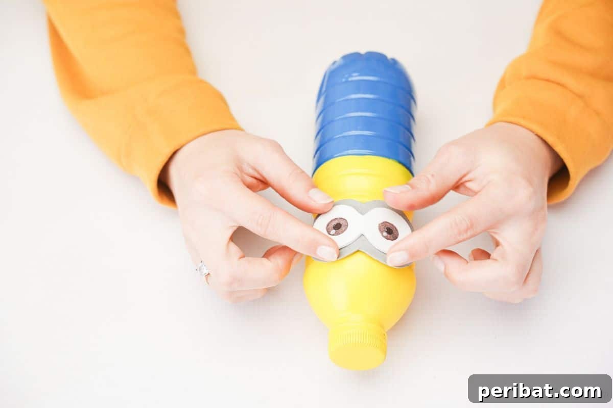Upcycled Bottle Minion Creations 15 A hand carefully glues the finished goggle assembly onto the Minion bottle, positioning it perfectly at the color seam.