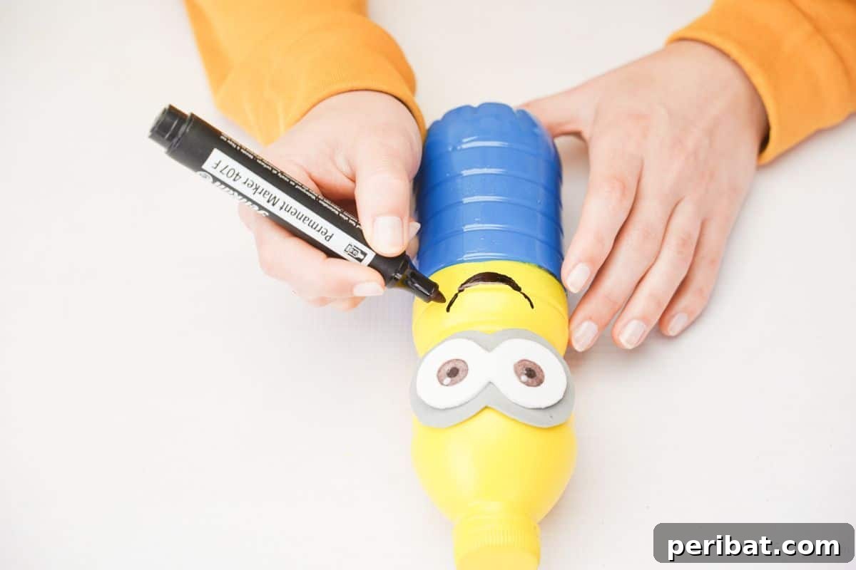 Upcycled Bottle Minion Creations 16 A black marker adds a playful smile to the plastic bottle Minion, completing its endearing expression.