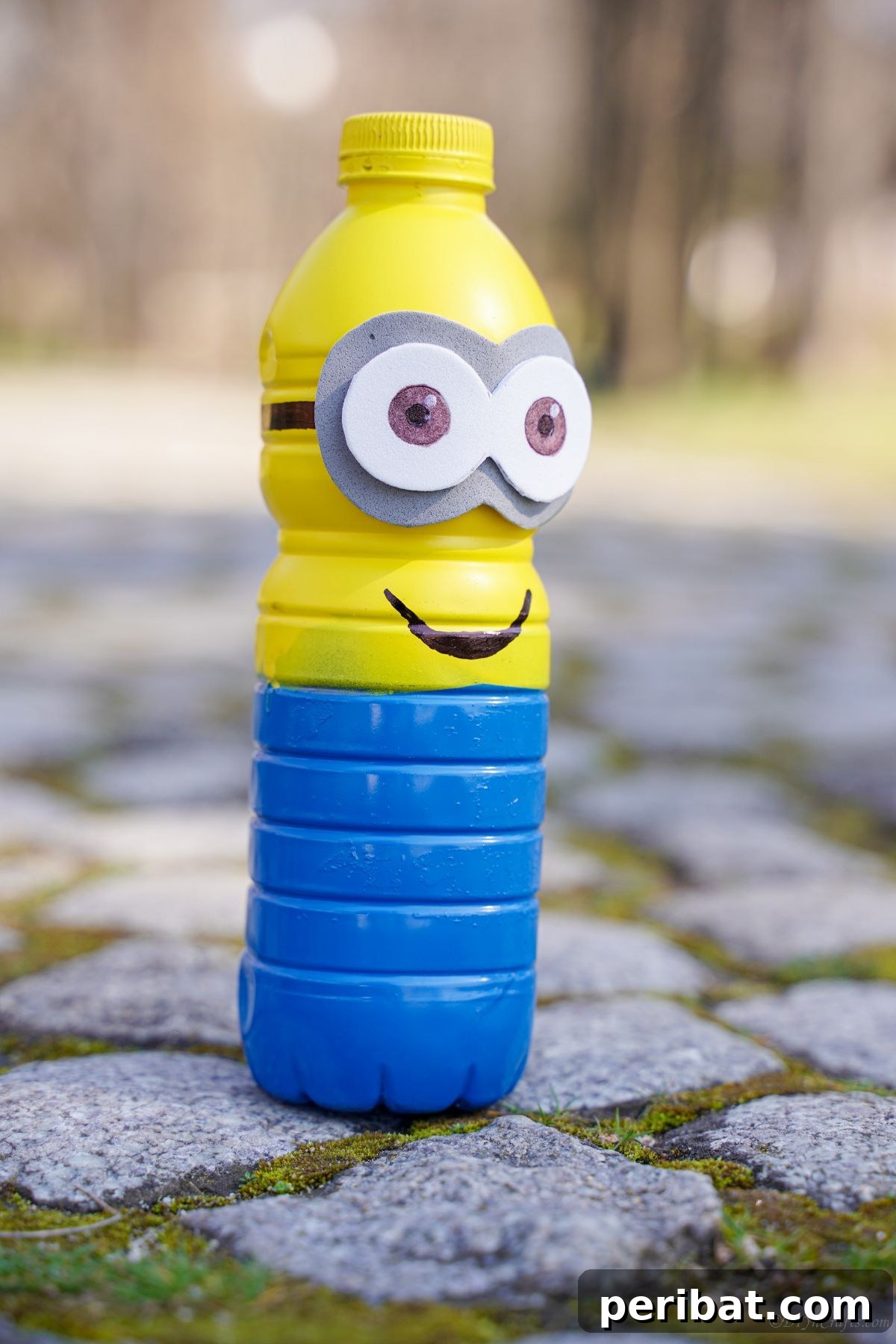 Upcycled Bottle Minion Creations 4 A charming plastic bottle Minion stands proudly on a rustic rocky path, showcasing its handmade appeal amidst natural surroundings.