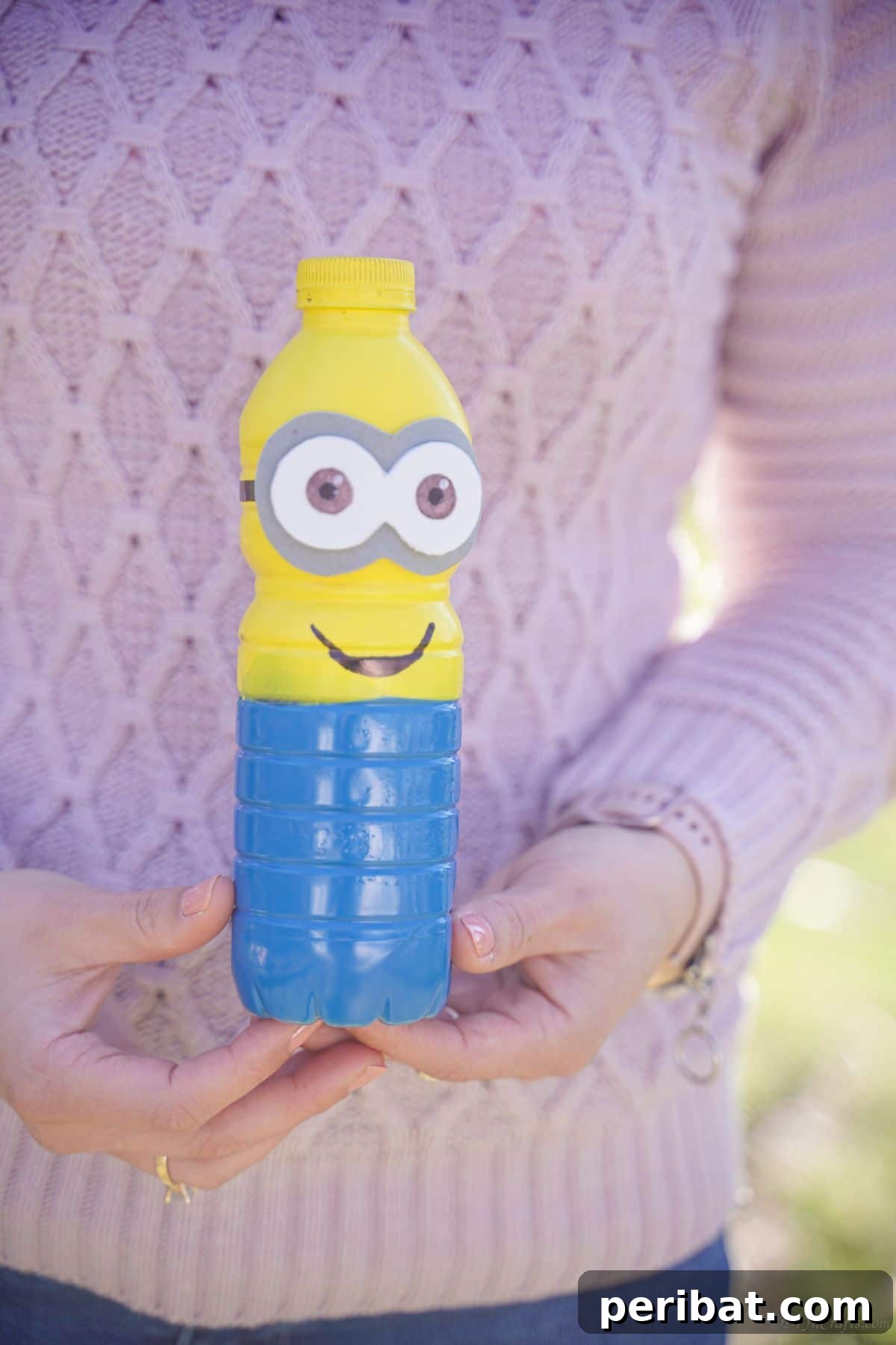 Upcycled Bottle Minion Creations 18 A lady in a pink sweater happily holds a finished plastic bottle Minion, demonstrating its delightful and huggable size.