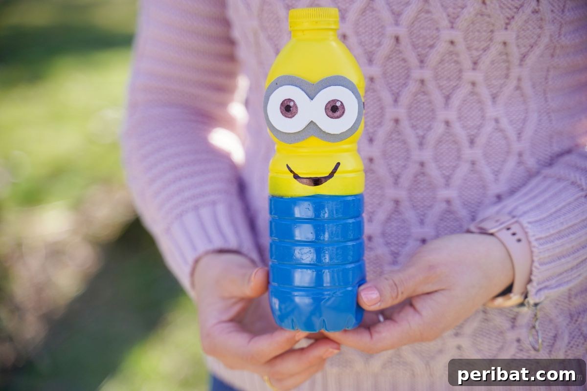 Upcycled Bottle Minion Creations 5 A person wearing a pink sweater gently holds a finished plastic bottle Minion, highlighting the craft's size and appeal.