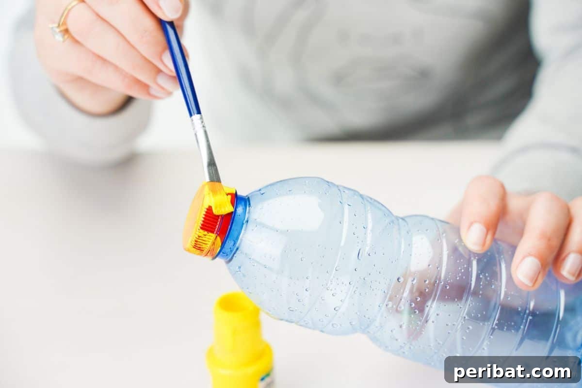 Upcycled Bottle Minion Creations 9 A hand expertly applies yellow paint to the upper half of a plastic bottle, transforming it into the Minion's iconic body.