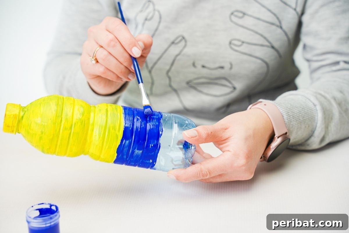 Upcycled Bottle Minion Creations 10 A person meticulously paints the lower half of the bottle blue, creating the Minion's signature overalls.